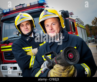 Due vigili del fuoco con il tubo flessibile e la gara Foto Stock