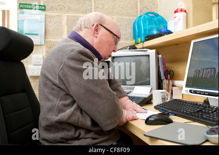 Un maschio di disabili con più di malformazioni congenite lavorando sulla linea telefonica di assistenza presso la sede di disabilità Essex. Foto Stock