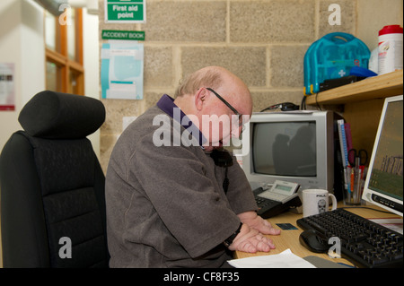 Un maschio di disabili con più di malformazioni congenite lavorando sulla linea telefonica di assistenza presso la sede di disabilità Essex. Foto Stock