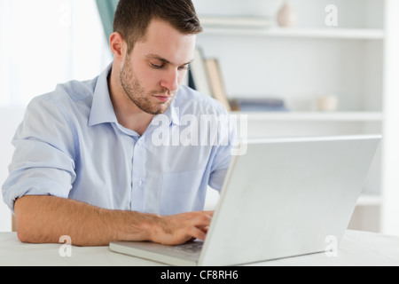 Imprenditore con arrotolato a maniche nel suo homeoffice sul suo computer portatile Foto Stock