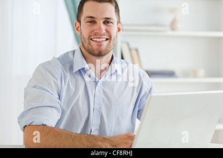 Imprenditore sorridente con arrotolato a maniche nel suo homebusiness Foto Stock