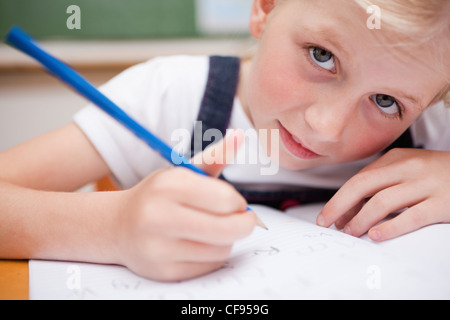 Close up di un grave schoolgirl scrivere qualcosa Foto Stock