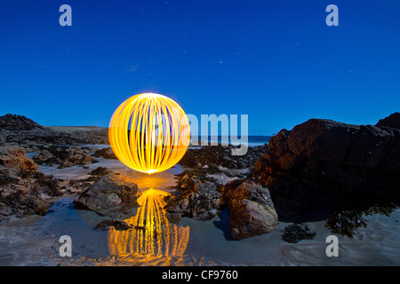 Luce dipinta orb presso una spiaggia rock pool. Creato da fotografie con lunghi tempi di esposizione e la filatura di una torcia su una catena Foto Stock
