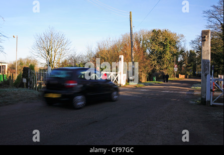 Un auto circa per attraversare la ferrovia Mid-Norfolk al passaggio a livello da Wymondham Abbey Stazione, Norfolk, Inghilterra, Regno Unito. Foto Stock