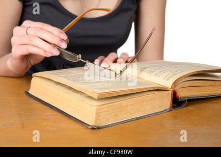 Le mani della ragazza con gli occhiali sopra il libro aperto isolata su uno sfondo bianco Foto Stock