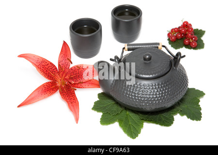 Teiera e due tazze con fiore del giglio rosso e wineberry Foto Stock