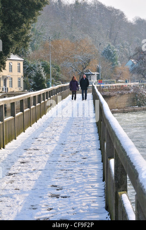 L uomo e la donna si cammina su strade coperte di neve passerella sul fiume Tamigi, a bloccaggio di palude, Henley-on-Thames, Berkshire, Inghilterra, Regno Unito Foto Stock