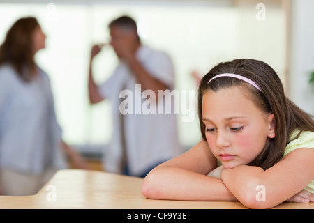 Ragazza triste con la sua lotta contro i genitori dietro di lei Foto Stock