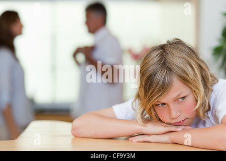 Triste cerca ragazzo con la lotta contro i genitori dietro di lui Foto Stock