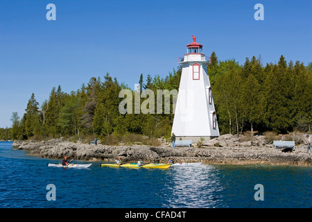 Pala Kayakers passato la grande vasca faro, Fathom cinque National Marine Park, Ontario, Canada. Foto Stock