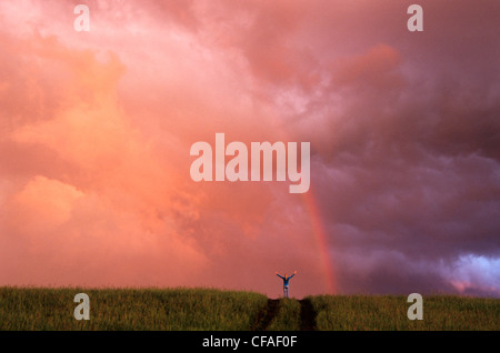 Ragazza sulla collina con le braccia aperte, nella parte anteriore del rainbow, vicino a Winnipeg, Manitoba, Canada. Foto Stock