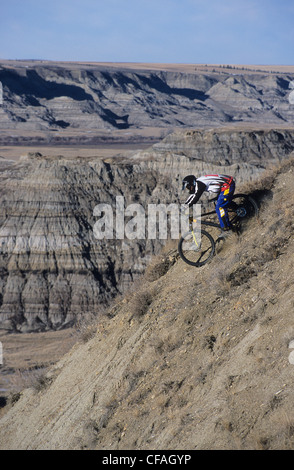 Un giovane uomo che discende su un passo ripido nel badlands in Drumheller, Alberta, Canada. Foto Stock