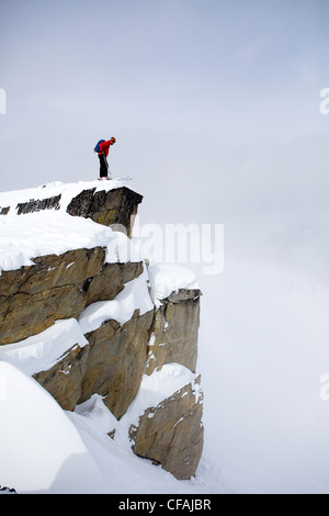 Uomo che guarda su una scogliera in Duffy la zona del lago di Monte Taylor, Coast Mountains, British Columbia, Canada. Foto Stock