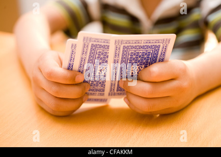 Mani tenendo le carte da gioco su un tavolo in una ricreazione e concetto di gioco d'azzardo Foto Stock