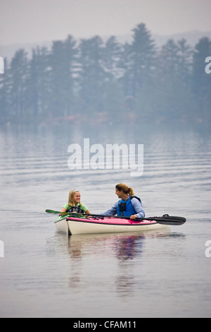 Giovani/di mezza età madre e figlia sea-kayak sul lago di origine, Algonquin Provincial Park, Ontario, Canada. Foto Stock