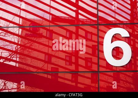 Un numero bianco 6 segno sulla facciata di colore rosso di un edificio per uffici a Londra, Regno Unito. Foto Stock