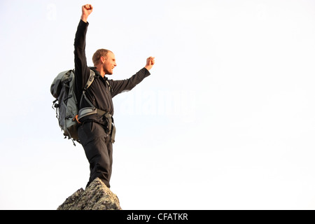 Giovane uomo alza il pugno in trionfo dopo aver scalato una montagna, Yukon, Canada Foto Stock