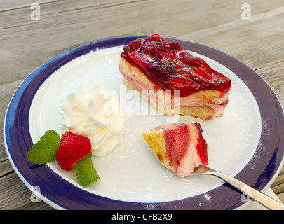 Mangiare più frutta: forca con un pezzo di torta di fragole panna montata su una lastra decorata per dessert Foto Stock