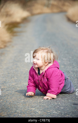 Baby Toddler ragazza bionda in esecuzione strada asfaltata campagna da soli Foto Stock