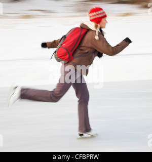 Movimento immagine sfocata di donna pattinaggio sul ghiaccio all'aperto. Fiume Assiniboine, Winnipeg, Manitoba, Canada. Foto Stock