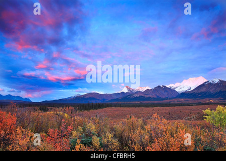 Nuvole illuminato dal sole che tramonta oltre il Fiume MacMillin valle con il Monte Itsi in distanza. Nord Canol Road, Yukon. Foto Stock