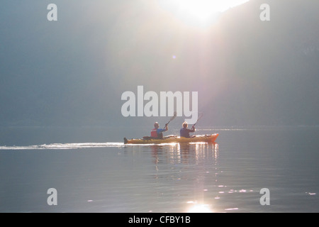 Kayakers paddling verso l'armonia le isole di Hotham Sound al tramonto lungo la British Columbia coast in Canada Foto Stock