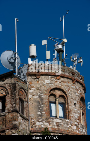 Schiera di antenne per telefonia mobile e antenne sulla parte superiore di una antica torre rotonda in Italia Foto Stock