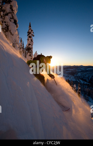 Una femmina di sciatore scende un pendio al tramonto nel Whitewater Resort invernale backcountry, British Columbia Foto Stock