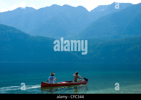 Due uomini paddling una canoa durante l'estate sul chiaro, acque blu del lago Slocan, British Columbia, Canada Foto Stock