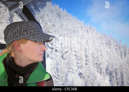 Donna che guarda fuori sopra coperta di neve montagna mentre equitazione in gondola. Montagna di zolfo, il Parco Nazionale di Banff, Alberta, Canada. Foto Stock