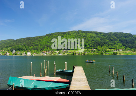 Pontile in legno con le barche a remi che conduce al lago Ossiacher See, Ossiach, lago Ossiacher See, in Carinzia Austria, Europa Foto Stock