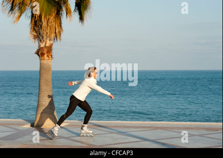 Pattinaggio lungo una spiaggia promenade, ripresa dalla telecamera panning Foto Stock