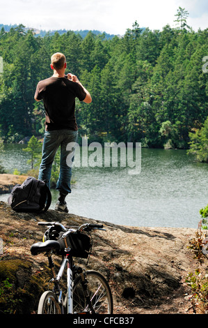 Mountain Biker tenendo la foto al lago Thetis Parco Regionale in Victoria, British Columbia, Canada Foto Stock