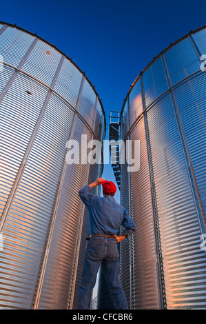 Un uomo si affaccia sul deposito di grano bin, vicino Lorette, Manitoba, Canada Foto Stock