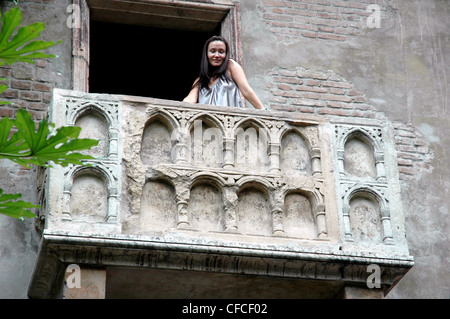 Una giovane donna pone, Giulietta simili, sul famoso balcone di Verona Italia Foto Stock