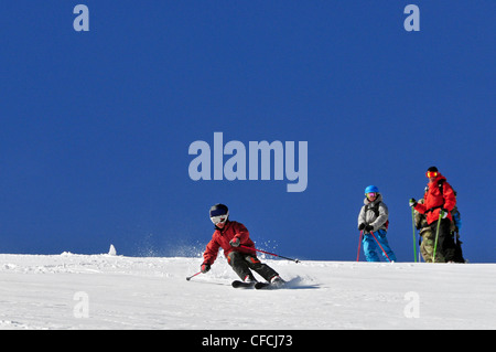 Un giovane maschio sciatore sci nel backcountry mentre il suo istruttore guarda a Kirkwood Mountain Resort, CA. Foto Stock