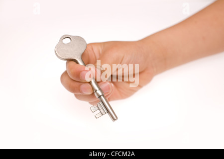 Bambino maschio lato tenendo premuto un tasto per la casa, l'immagine viene presa su uno sfondo bianco. Foto Stock