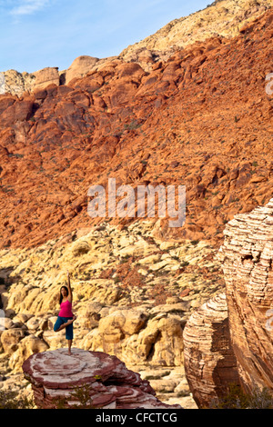 Montare una giovane donna asiatica a praticare yoga durante una scalata su roccia viaggio, Red Rocks, Las Vegas, Nevada, Stati Uniti d'America Foto Stock