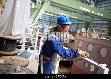 Lavoratore ringhiera di pittura, cruiser in costruzione nel bacino di carenaggio, Meyer Werft, Papenburg, Bassa Sassonia, Germania Foto Stock