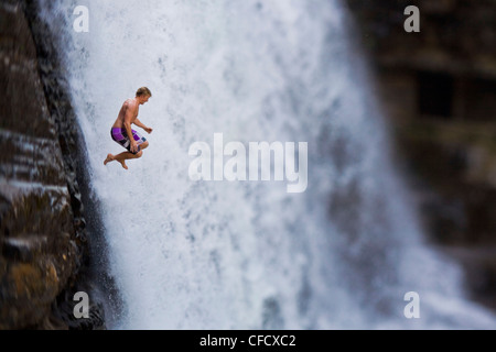 Un giovane uomo ciff immersioni subacquee a Moyie Falls, Cranbrook, British Columbia, Canada Foto Stock