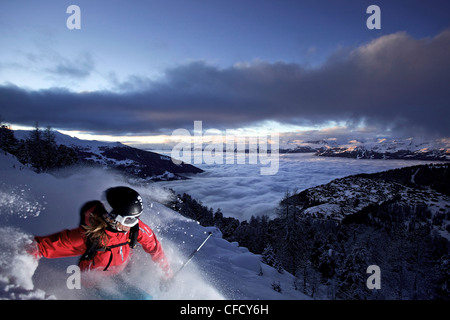 Sciatore femmina nella neve profonda al crepuscolo, Chandolin, Anniviers, Vallese, Svizzera Foto Stock