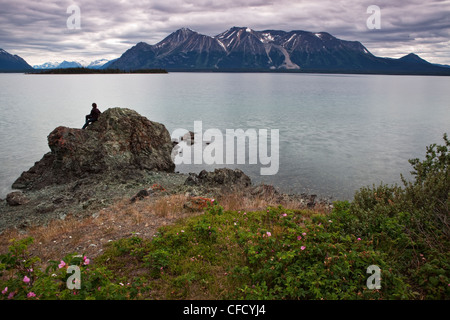 Donna seduta su roccia, Atlin Lake, British Columbia, Canada. Foto Stock