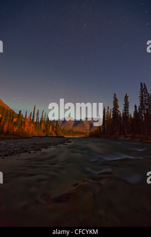 Wheaton River di notte con meteor scatti sopra le montagne. Debole aurora visto come bene. Yukon, Canada. Foto Stock