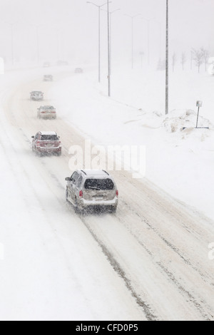 Il traffico su una coperta di neve su strada, durante una tempesta di neve in inverno. Winnipeg, Manitoba, Canada. Foto Stock