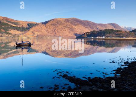 Pittoresco e tranquillo Loch Leven con barca a vela e dalla riflessione di Glen Coe village, Highlands, Scotland, Regno Unito Foto Stock