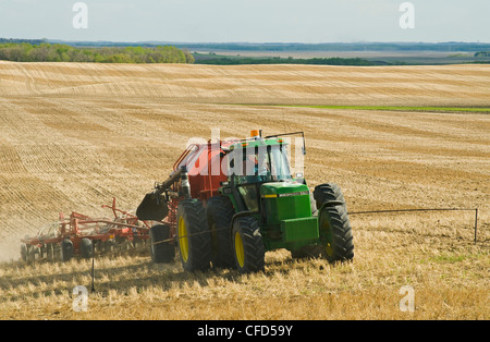 Trattore in movimento e aria fino a una seminatrice di piantare la canola in uno zero fino a grano campo di stoppie, Bruxelles, Manitoba, Canada Foto Stock