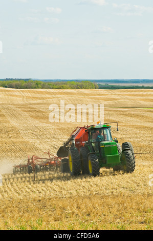 Trattore in movimento e aria fino a una seminatrice di piantare la canola in uno zero fino a grano campo di stoppie, Bruxelles, Manitoba, Canada Foto Stock