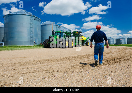 Un uomo cammina verso l'apparecchiatura per la semina in cortile vicino a Torquay Saskatchewan, Canada Foto Stock