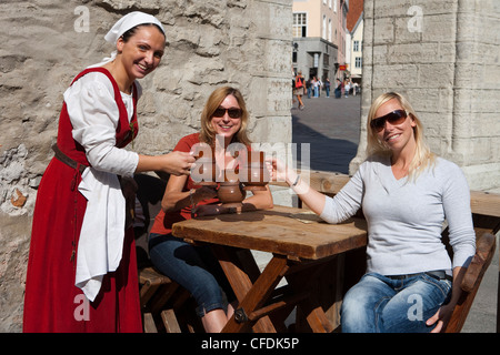 Cameriera in costume medievale e turisti con boccali di birra al ristorante Olde Hansa nella piazza del Municipio (Raekoja plats), Tallin Foto Stock