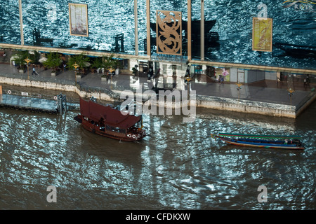 La riflessione di vetro di barche accanto al Fiume città sul fiume Chao Praya River visto dal Millennium Hilton Hotel, Bangkok, Thailandia Foto Stock